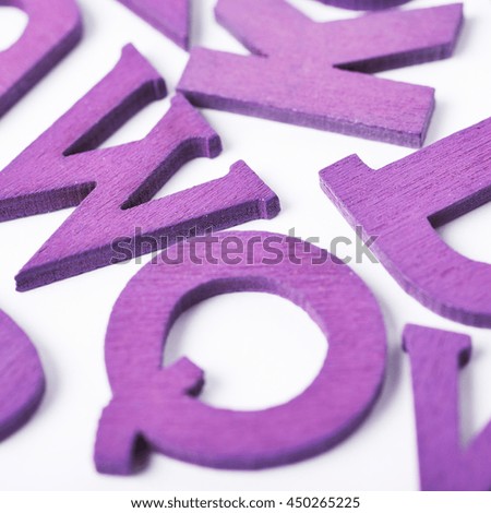 White surface covered with the multiple colorful violet painted wooden letters as a backdrop composition
