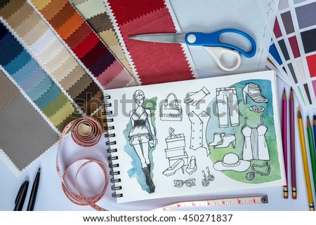 Fashion designer studio with sketch of clothes, equipment and samples on table  / garment business concept