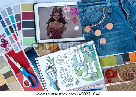 Fashion designer studio with sketch of clothes, equipment and samples on table  / garment business concept