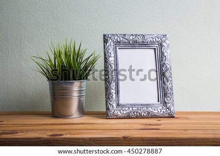 Silver vintage photo frame with tree decoration on wooden table over wall background