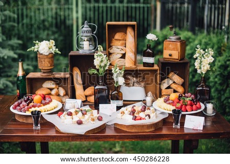 Wedding decorations. Reception. Buffet. Fruits and cheese on plates with bread in boxes. Food bar decorated by flowers and lanters Royalty-Free Stock Photo #450286228