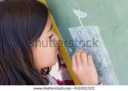 Brunette girl details building on blackboard using chalk