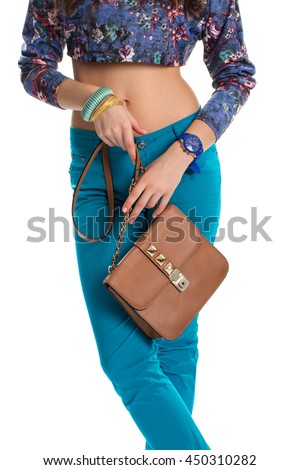 Woman with brown bag. Blue pants and crop top. Leather purse of high quality. Set of casual accessories.