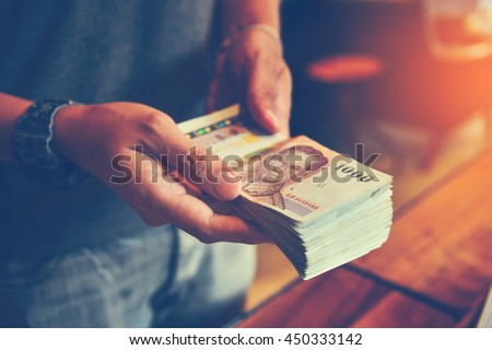 Hands counting Thai Baht bills. Toned picture
