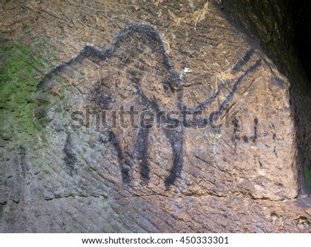 Abstract children art in sandstone cave. Black carbon mammoth paint of human hunting on sandstone wall, copy of prehistoric picture.