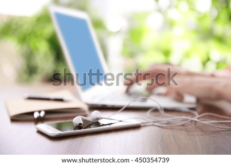 Female hands working with a laptop outdoor on blurred green plant background
