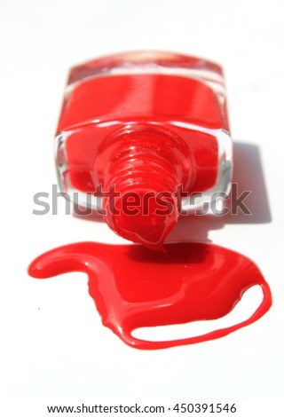 Red nail polish (enamel) drops with bottle on white background