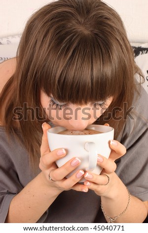 Girl with a cup of cappuccino on a sofa