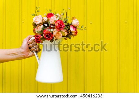 Hand holding a flower with yellow background