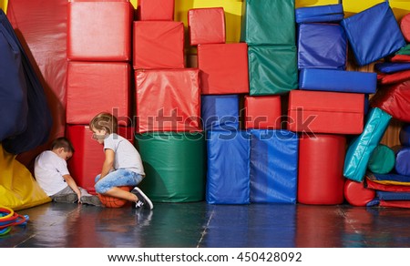 Sad child sitting in corner of gym and boy tries to comfort him