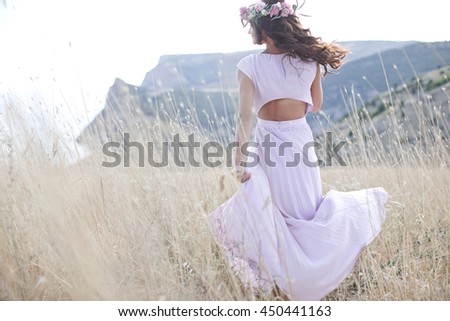 Attractive young woman with flower wreath on her head with sunset in background.