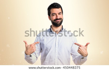 Man proud of himself over ocher background Royalty-Free Stock Photo #450448375