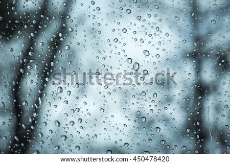 rain drops on glass with trees silhouette background