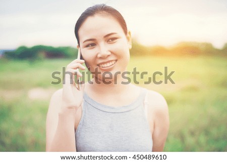 Young beautiful woman using smartphone and smiling in the park.
