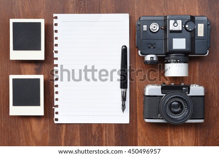 paper with pen, photo frames and camera on wooden background.