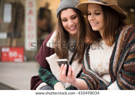 Trendy young women using smartphone in the city