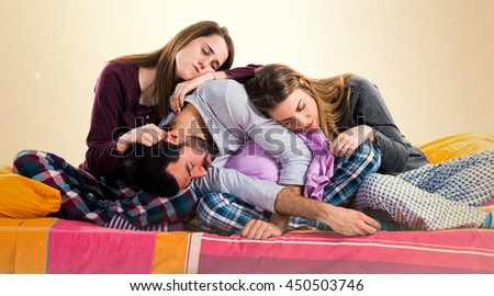 Three friends on a bed sleeping over ocher background