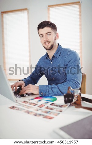 Portrait of confident young man working on laptop at office