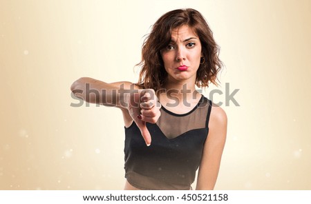 Woman doing bad signal over ocher background