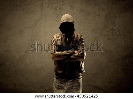 A suspicious faceless mature male in dark urban environment and light in front of a concrete empty wall background