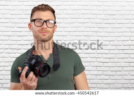 Portrait of a handsome young in glasses man with camera