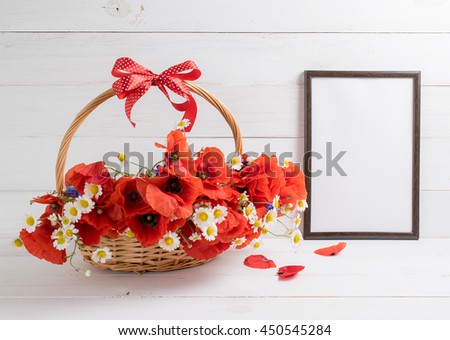 Red poppies bouquet in basket with bow and motivational frame for your text or picture on background of white wooden planks in scandinavian style