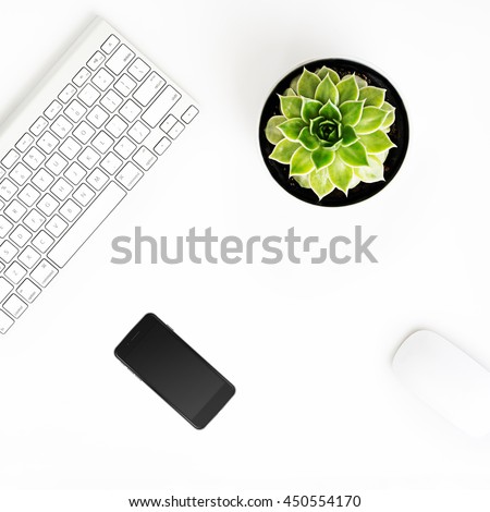 White office desk table with wireless aluminum keyboard, smart phone in iphon style with black screen, mouse and succulent flower in pot. Top view with copy space. Flat lay. 
