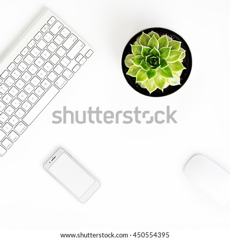 White office desk table with wireless aluminum keyboard, smart phone in iphon style with blank screen, mouse and succulent flower in pot. Top view with copy space. Flat lay. 
