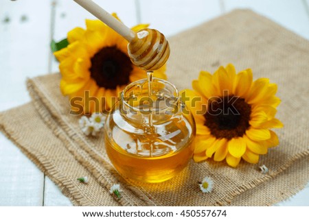 Honey jar with dipper and flowing honey, canvas background