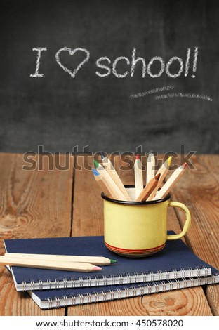 Still life, business, education concept. Pencils in a mug and notebook on a wooden table with chalkboard. Selective focus, copy space background