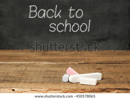 Still life, education concept. Pieces of chalk on a wooden background and chalkboard. Selective focus, copy space school background