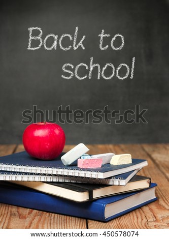 Still life, business, education concept. Chalk pieces, notebooks and apple on a wooden table with chalkboard. Selective focus, copy space, school background