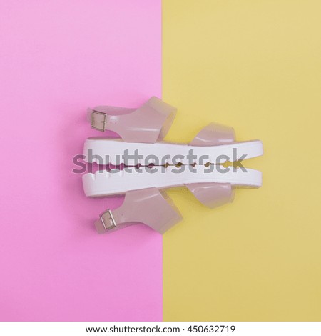 fashion minimalism: sidepiece of plastic transparent sandals with white platform on pink and yellow backgrounds