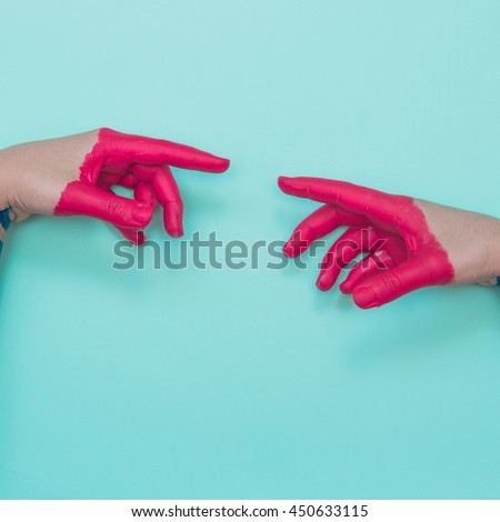 Two painted hands try to reach each other's fingers. Creative connecting conception.  Royalty-Free Stock Photo #450633115