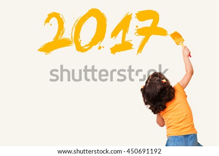 Cute little girl drawing new year 2017 with painting brush on wall background Royalty-Free Stock Photo #450691192