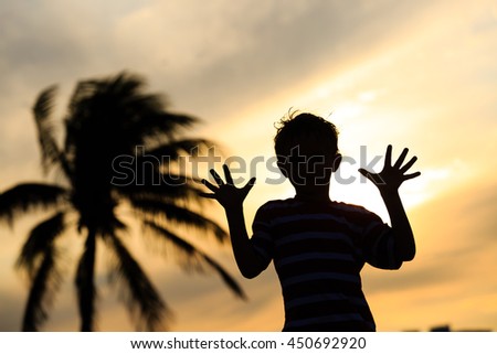 Silhouette of little boy play at sunset beach
