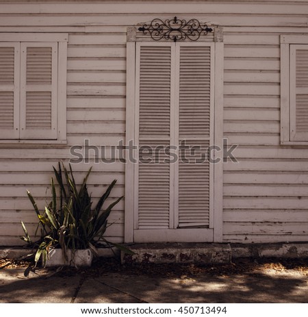 old wooden white door and windows on a white wooden wall with a small plan growing close to it in the autumn. Miami. Bahia Honda Park. Florida. USA.