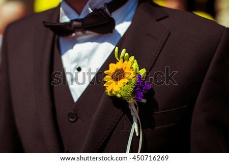 Boutonniere made of sunflower pinned to the black jacket