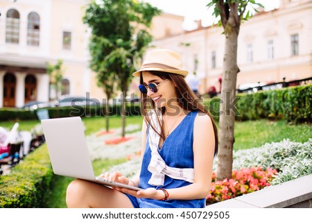Pretty girl working with laptop sitting on stairs of city street. Urban life concept