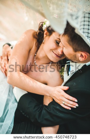 Bride and groom in a park kissing under tent fabric.couple newlyweds bride and groom at a wedding in nature green forest are kissing photo portrait.Wedding Couple