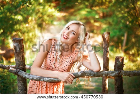beautiful smiling young girl in the summer garden near the fence