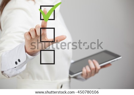 Young business woman checking on checklist box. Gray background. Royalty-Free Stock Photo #450780106
