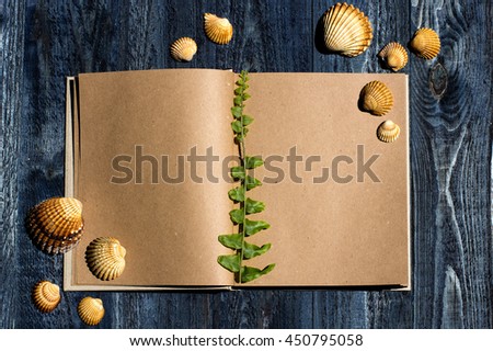 notebook with fern leaf and sea shells on the blue wooden background