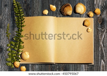 notebook with fern leaf and sea shells on the grey blue wooden background