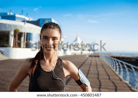 Picture of young smiling fitness girl with sea coast on background