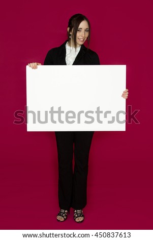 Smiling young business woman wearing a business suit standing behind looking down at a white board against pink background