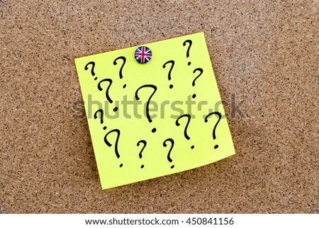 Yellow paper note pinned on cork board with Great Britain flag thumbtack, question marks, United Kingdom exit from European Union