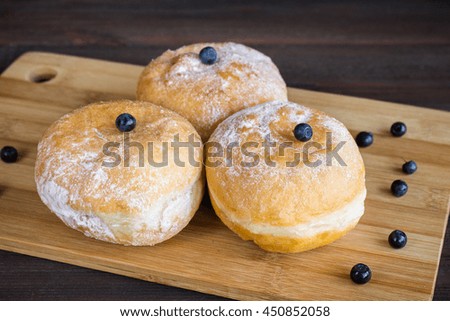 blueberry donuts sprinkled with icing sugar on wooden background