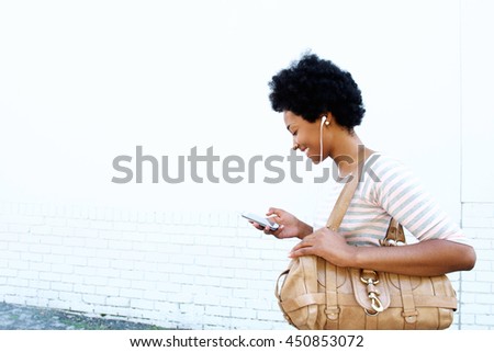 Side profile portrait of smiling woman looking at cellphone