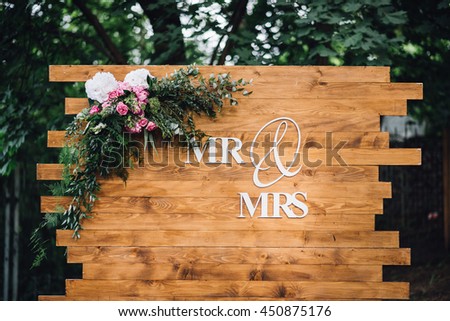 Wedding. Banquet. Mr. & Mrs. signs on wooden board decorated by flowers and greenery. Royalty-Free Stock Photo #450875176